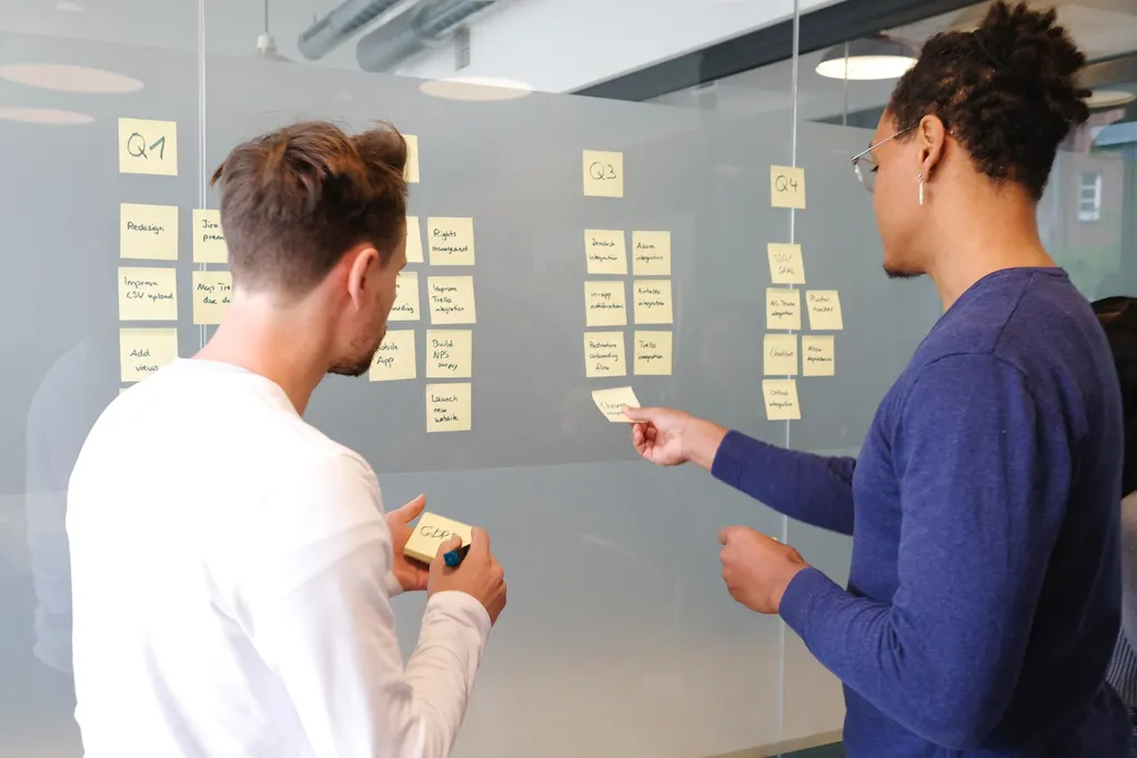 An image of 2 people posting sticky notes on their business board