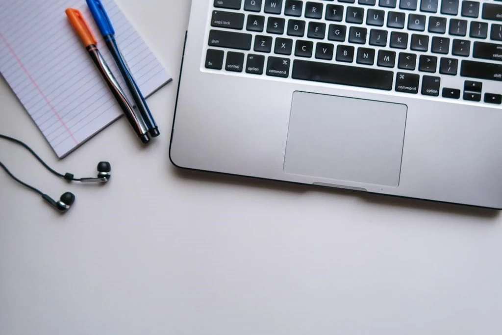 Laptop with pen and paper beside it