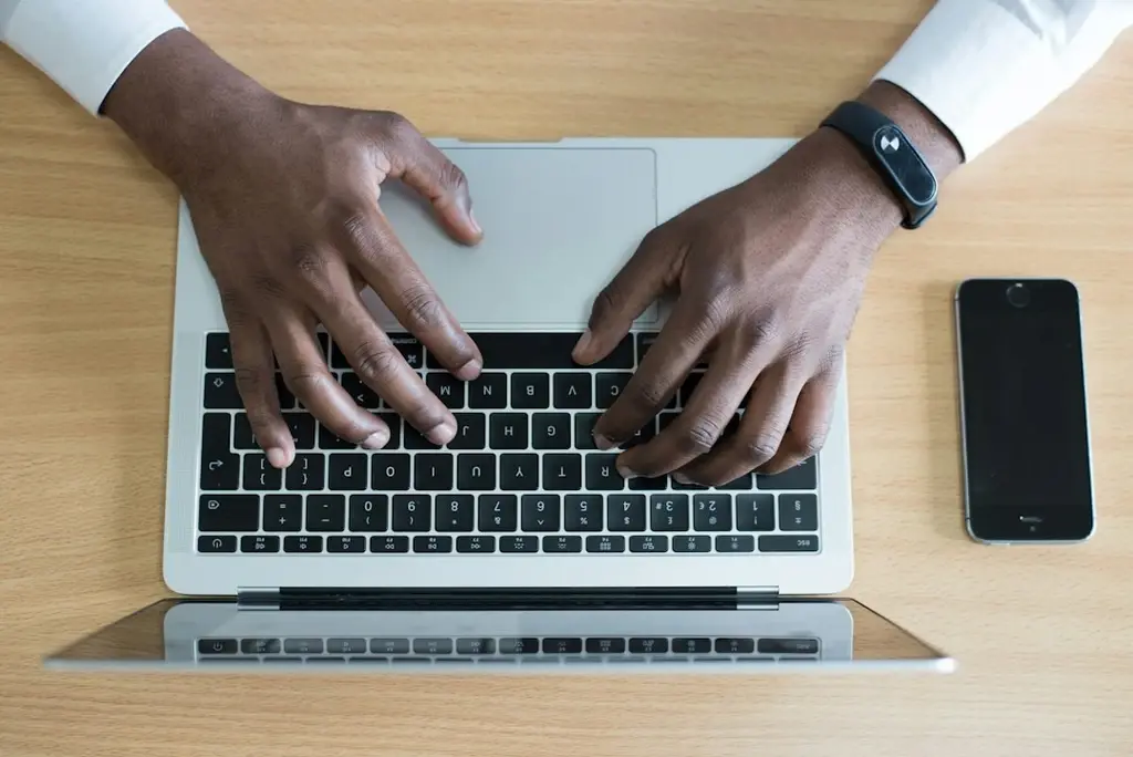 A man's hand typing in a keyboard's laptop